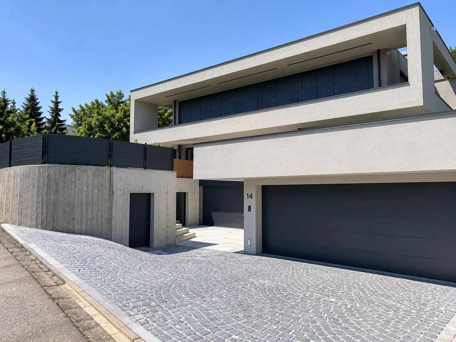 Einfahrt vor einem modernen Wohnhaus, gepflastert mit grauem Kleinpflaster im Segmentbogen