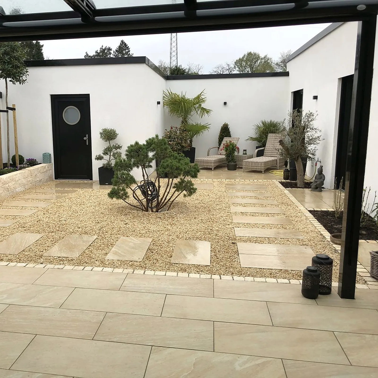 Innenhof mit hellem Kies, Trittplatten, einer Kiefer als Solitär und großformatiger Terrasse