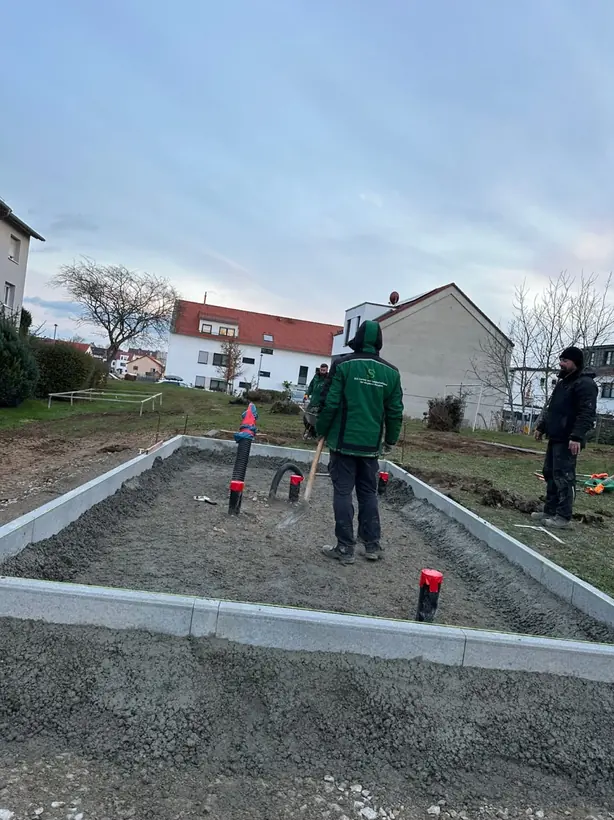 SGL-Mitarbeiter auf dem Schotterunterbau einer neuen Fläche mit Randsteinen und Entwässerung